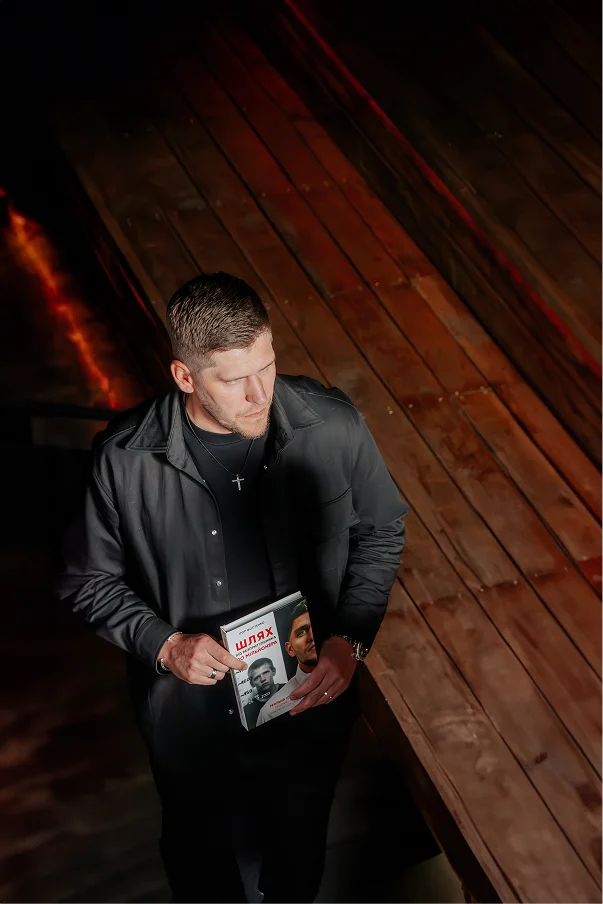 Ihor Fostenko holding a magazine with a wooden interior background

